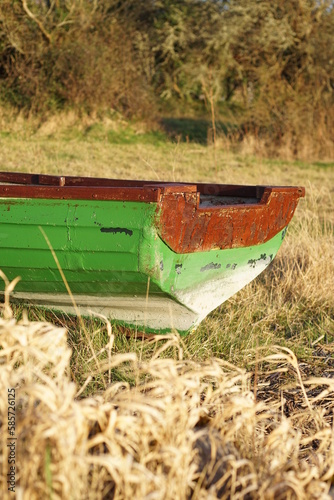 Close up of back of small green wooden row boat aground in field near Lough Colgagh, County Sligo, Ireland on springtime evening