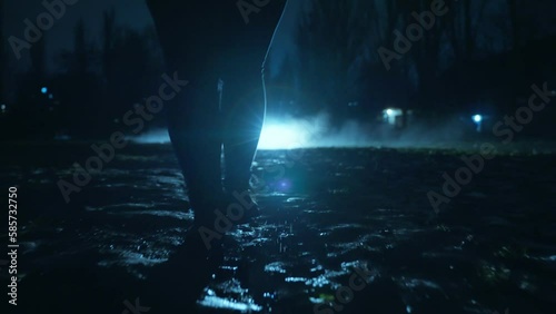 A people walks along the alley of the night city after the rain through the fog
