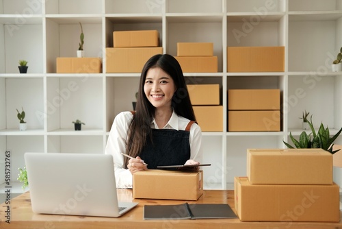 Portrait of young Asian woman working SME with a box at home the workplace.start-up small business owner, small business entrepreneur SME or freelance business online and delivery concept. © Sucharat
