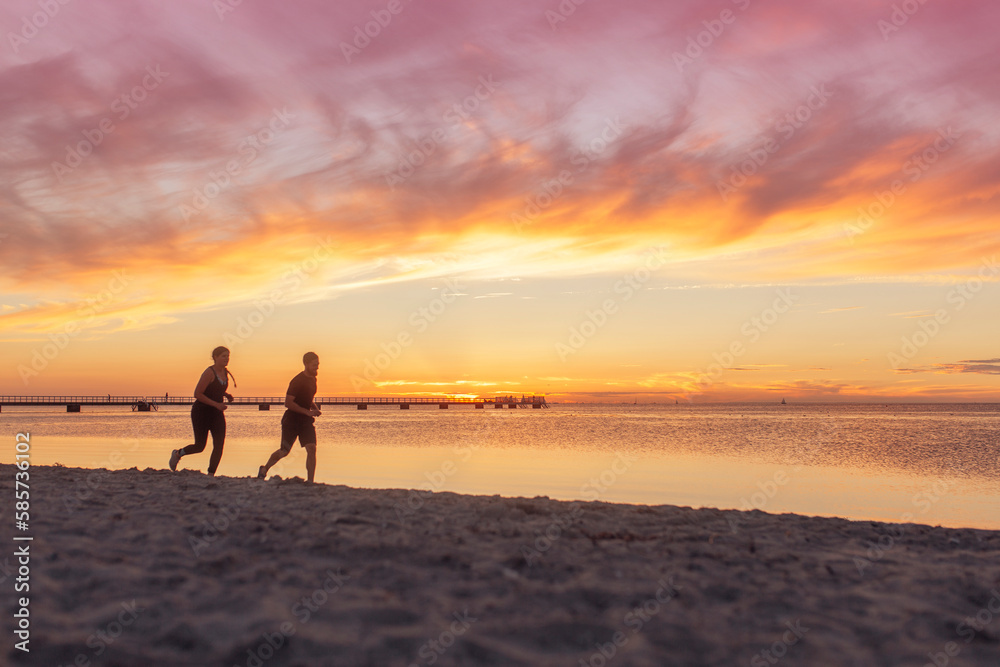 Young couple running on beach at sunset Young couple running on beach at sunset