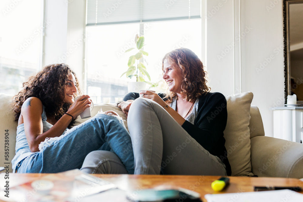 Two women sitting on sofa and drinking coffee Two women sitting on sofa and drinking coffee