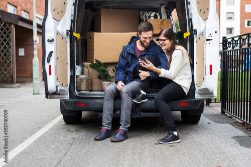Man and woman resting in rental car and looking at smart phone