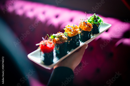 woman waiter holding plate with Set Gunkan Maki Sushi in restaurant