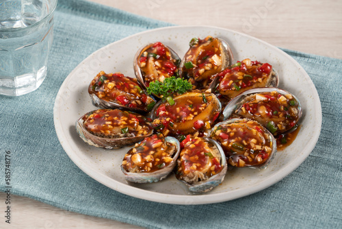 Delicious steamed abalone with Taiwanese five flavor sauce on wooden table background.