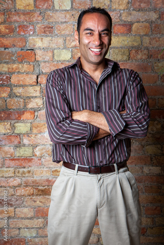 A Friendly Face. A relaxed smile and eye contact from a smartly dressed, handsome South Asian man in a striped shirt. From a series of related images.