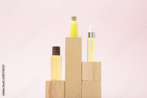 Composition of three small bottles with a yellow cosmetics products and wooden podiums blocks. Minimalism