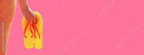 Close up woman holding flip flops on pink background, summer vacation concept, blank copy space for advertising text