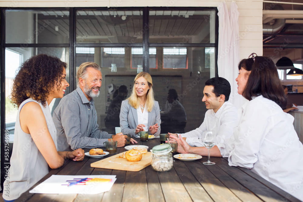 Business people sitting by wooden table and talking Business people sitting by wooden table and talking