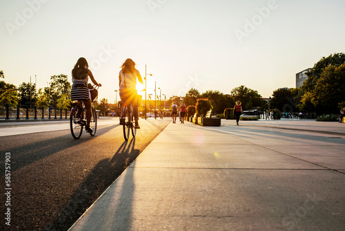Women cycling in city at sunset