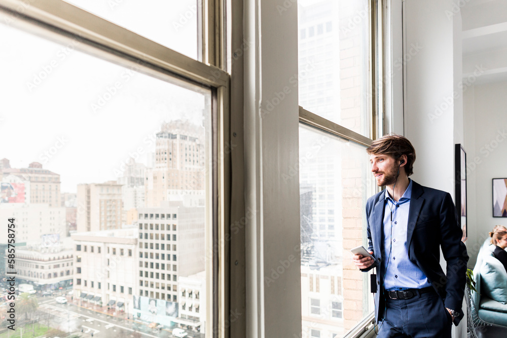 Young businessman looking through window Young businessman looking through window