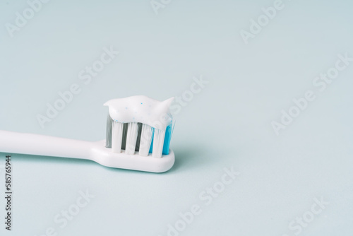 Toothbrush with toothpaste on blue background.