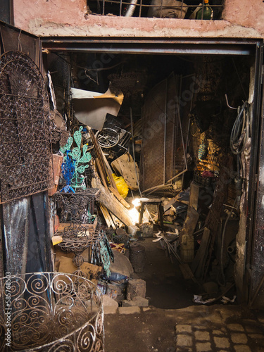 Rays of light in a dark, crowded garage in the busy Souk market alley selling and welding metal wares in the heart of the Medina of Marrakech, Morocco, dark street with sunlight
