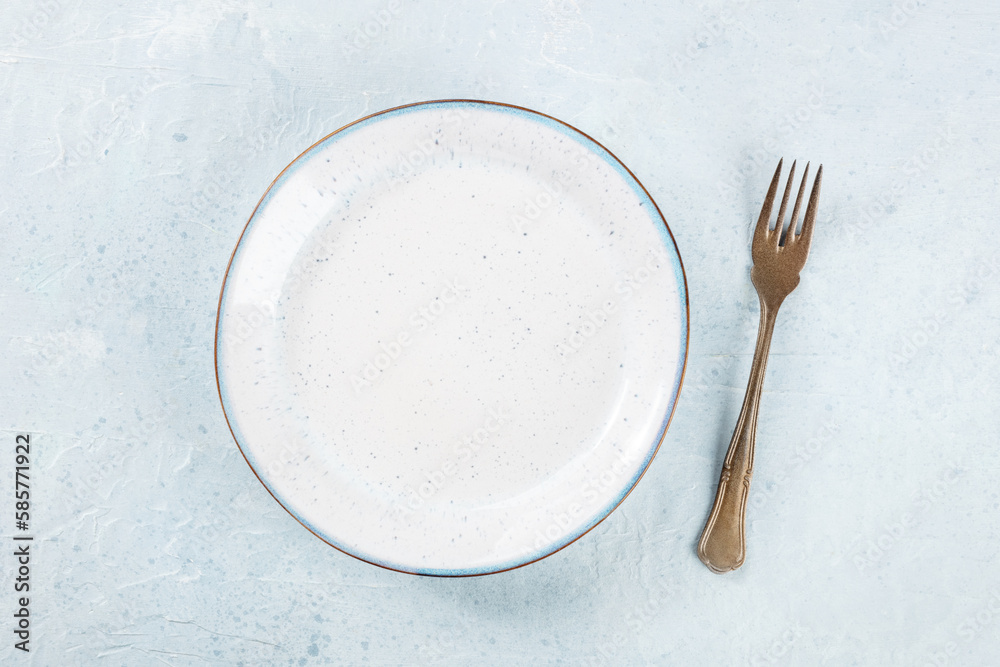 An empty white plate with a blue rim, with a fork, overhead flat lay shot, the concept of food