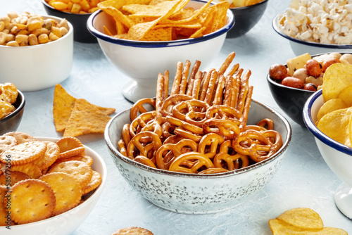 Salty snacks, party mix. An assortment of crispy appetizers in bowls on a table. Crackers, sticks etc