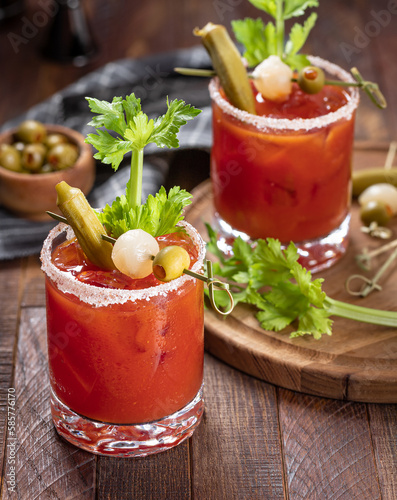 Bloody mary cocktail with garnishes on rustic wooden table