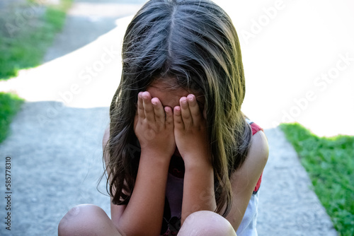 Criança com mão no rosto e deprimida com simulação de abuso.
