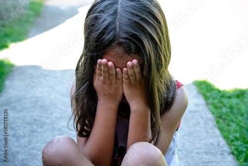 Criança com mão no rosto e deprimida com simulação de abuso.
