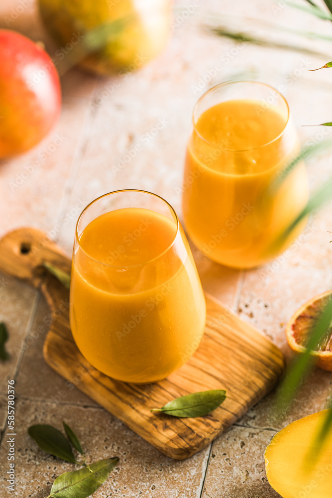 Two mango lassi or kesar milk in glasses. Indian healthy ayurvedic cold drink with mango. Freshness lassi made of yogurt, water, spices, fruits and ice. Two mango lassi or kesar milk in glasses. Indian healthy ayurvedic cold drink with mango. Freshness lassi made of yogurt, water, spices, fruits and ice.
