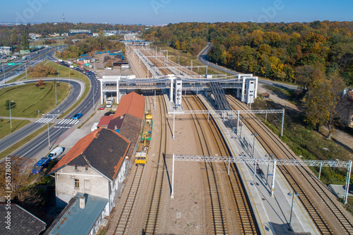 Poland. Kraków- Bonarka railway station with tracks, platforms, footbridge, passenger overpass, stairs and lifts. Multilane road with slip roads and junctions on the left. Aerial view
