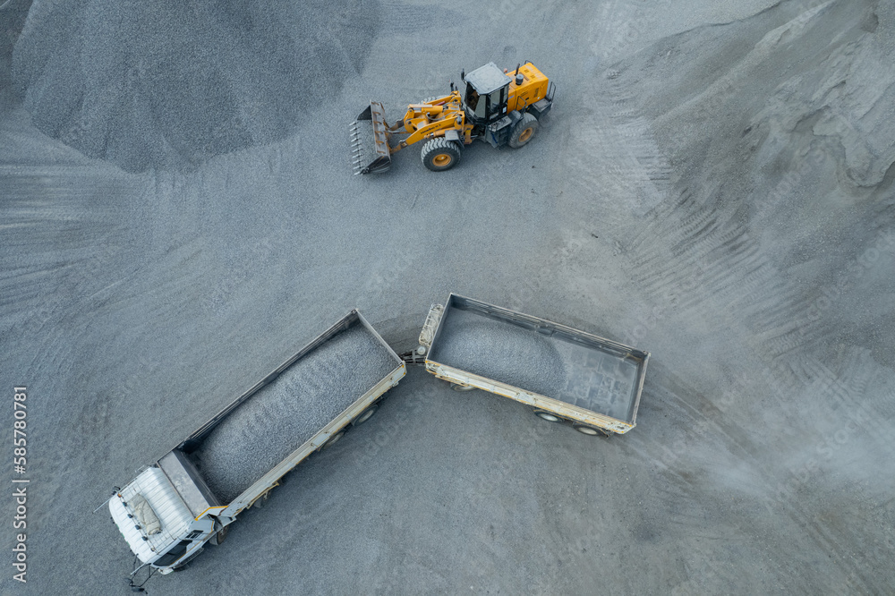 Sand loaders are shoveling rocks into dump trucks.