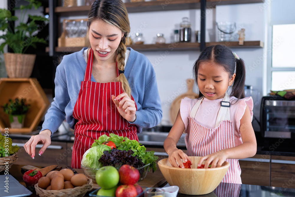 Young mother teach daughter in the kitchen learn online cooking clean food from the laptop computer Young mother teach daughter in the kitchen learn online cooking clean food from the laptop computer