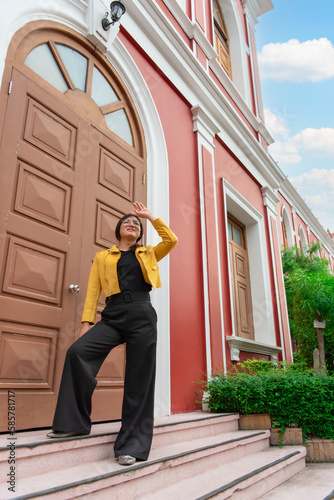 Beautiful asian woman (LGBTQ) natural makeup wear fashion yellow leather clothes with glasses posing at old town and vintage building outdoor fashion style photo