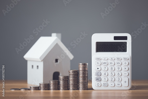 Bank interest for home, Interest rate for housing, Business and Financial for residence, Money saving for home concept. Increasing coin stacked and house model on the wooden table. © SKT Studio