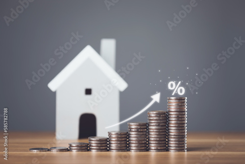 Bank interest for home, Interest rate for housing, Business and Financial for residence, Money saving for home concept. Increasing coin stacked and house model on the wooden table.