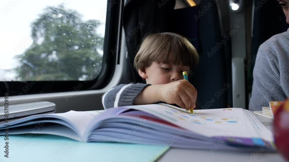 Child holding coloring pen on paper while traveling by train in motion. One little boy doing homework. Closeup kid holds crayon studying Child holding coloring pen on paper while traveling by train in motion. One little boy doing homework. Closeup kid holds crayon studying