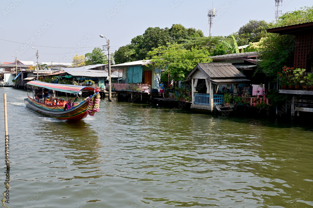 BANGKOK, THAILAND - MARCH 30, 2023 : Tourist Passenger Boat leading tourists to view the houses along the canal and the ways of villagers along the canal in the Chao Phraya River Canal.
