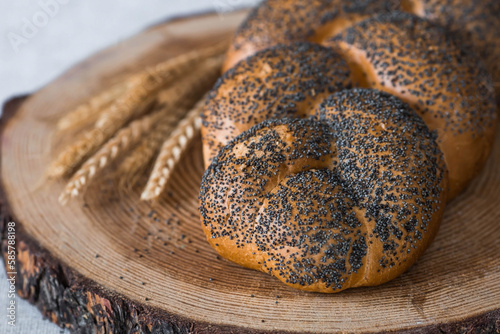 Classic wheat braid with poppy seeds. Delicious bread close-up. Freshly baked sourdough bread with a golden crust on a wooden board. The context of a bakery with delicious bread.  photo