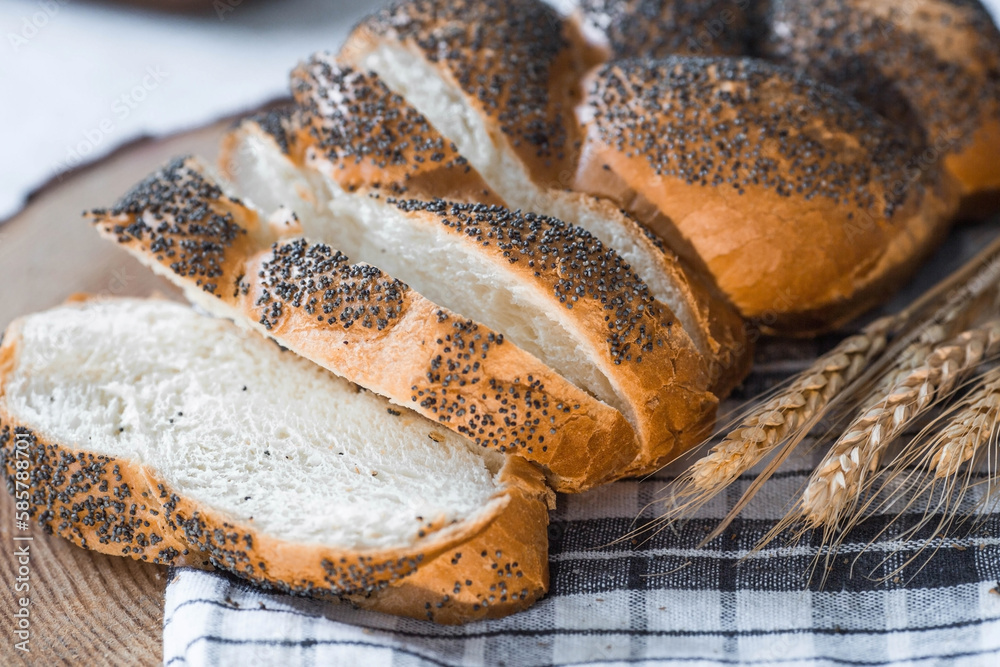 Classic wheat braid with poppy seeds. Delicious bread close-up. Freshly baked sourdough bread with a golden crust on a wooden board. The context of a bakery with delicious bread. 