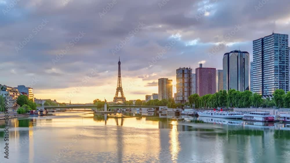 Eiffel Tower sunrise timelapse with boats on Seine river and in Paris, France. Aerial view from Mirabeau bridge with dramatic sky. Modern buildings and traffic on a road. The Statue of Liberty Eiffel Tower sunrise timelapse with boats on Seine river and in Paris, France. Aerial view from Mirabeau bridge with dramatic sky. Modern buildings and traffic on a road. The Statue of Liberty