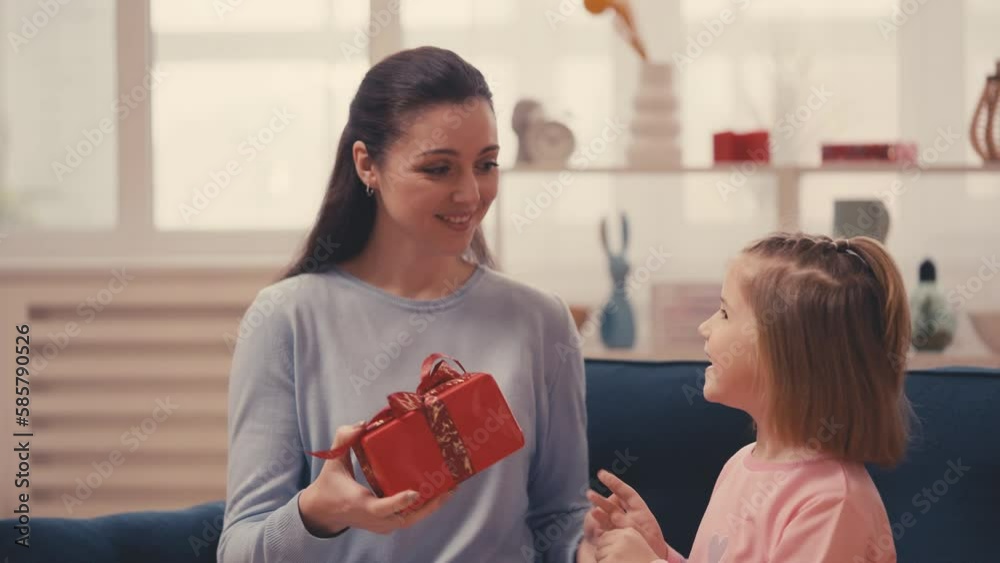 Little girl runs to her mom, presenting a red gift box, celebrating Mother's Day