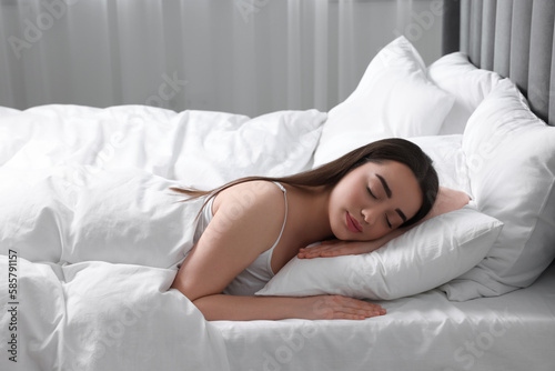 Beautiful young woman sleeping in soft bed at home