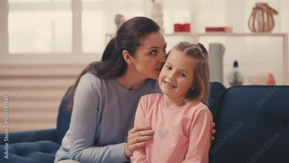 Caring mother kisses the head of her little daughter, warm family relationship