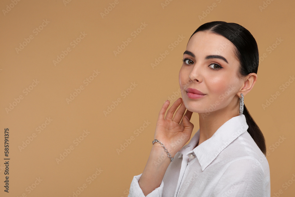 Beautiful young woman with elegant jewelry on beige background. Space for text Beautiful young woman with elegant jewelry on beige background. Space for text