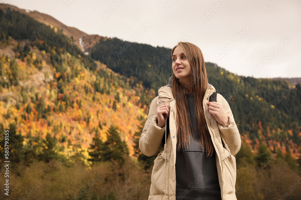 Happy woman with backpack in beautiful mountains, low angle view. Space for text
