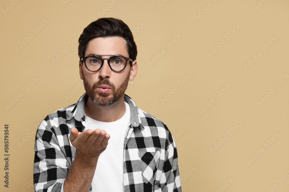 Handsome man blowing kiss on beige background. Space for text Handsome man blowing kiss on beige background. Space for text