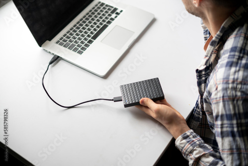 holding backup external hdd with archive and connect it to the laptop photo