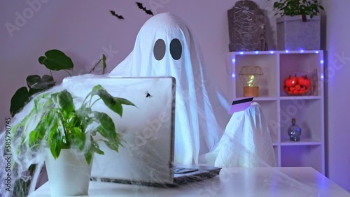 Ghost of Halloween uses laptop surf the Internet, browse online stores, markets. A ghost makes an order from computer for Halloween. Ghost pays for online purchase by credit, bank card.