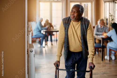 Foto Pensive black senior man with mobility walker by window in nursing home