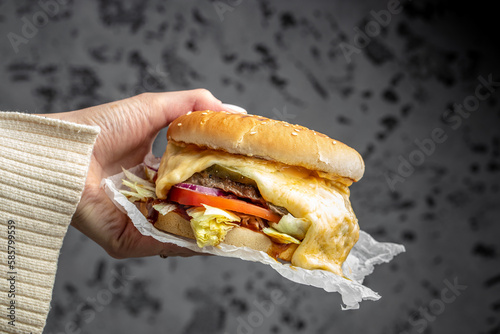cheeseburger. melted cheese burger in hand. Fast food take away. copy space