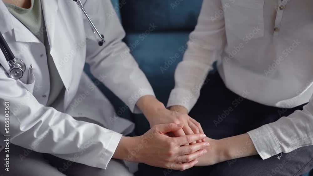 Doctor reassuring patient while sitting and discussing something near each other on a blue sofa. Empathy in medicine concept
