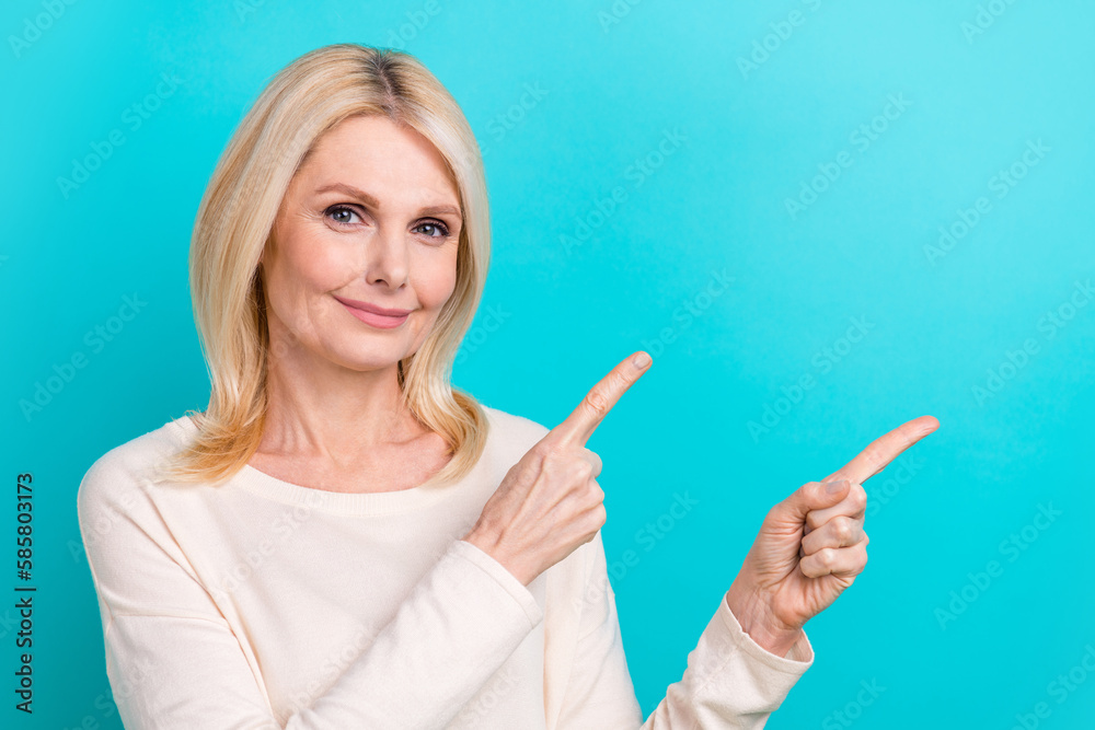 Photo of mature age confident woman wear white shirt directing fingers empty space useful info for coworkers isolated on cyan color background Photo of mature age confident woman wear white shirt directing fingers empty space useful info for coworkers isolated on cyan color background