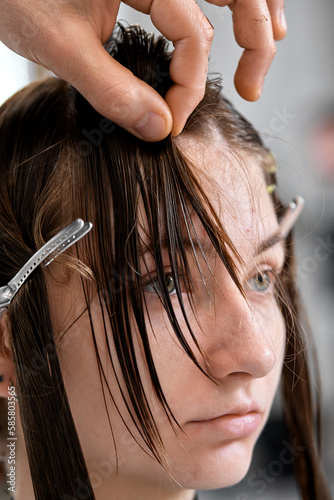 Professional male hairdresser cutting female hair