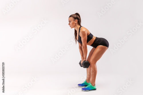 Beautiful young athletic girl in shorts and top lifts with dumbbells. Fitness woman working out with dumbbells. Sports, healthy lifestyle.