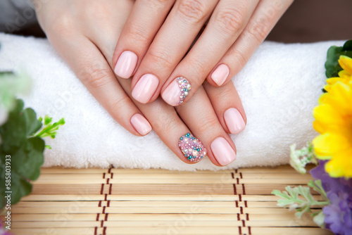 Manicure. A beautiful woman s manicure. Women s hands on placenta and flowers with a beautiful manicure. Woman grooming her hands. Hands and spa relaxation. Beauty woman nails.