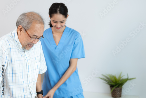 Asian nurse support senior elderly male, Asian older aged man doing physiotherapist in home living room using walker workout exercise for patient with caregiver in health insurance nursing care