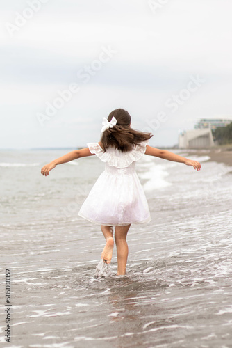 Happy child running and jumping in the waves during summer vacation on tropical beach. Holiday on ocean coast for family with young children. Kids play at the sea.
Adorable little girl running and lau